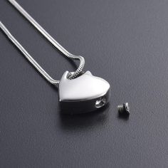 a heart shaped pendant is shown on a black surface next to two ear plugs