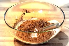 a glass bowl filled with spices on top of a wooden table