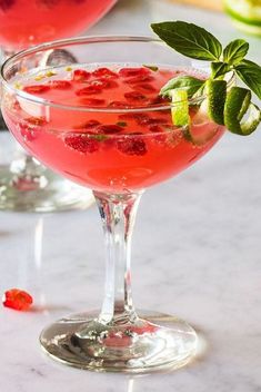 two glasses filled with fruit and garnish sitting on a table next to each other