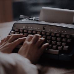 a person typing on an old fashioned typewriter with their hands and the letters brother de luxe