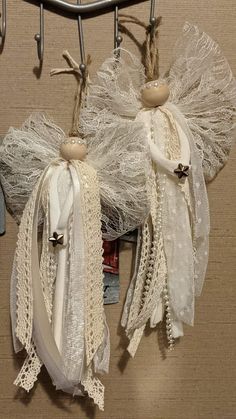 two angel ornaments hanging from a metal rack on a brown carpeted wall next to scissors and other items