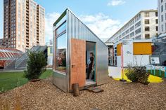 a small metal structure in the middle of a park with trees and buildings behind it