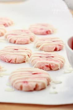 cookies with white icing are on a tray next to a cup of tea and sauce