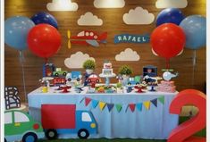 a table topped with balloons and cake next to a number two sign in front of a wall