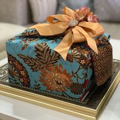 a blue gift box sitting on top of a table next to a gold tray with an orange bow