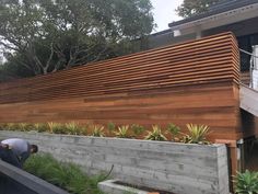 a man is working on the side of a house with wood slats and succulents