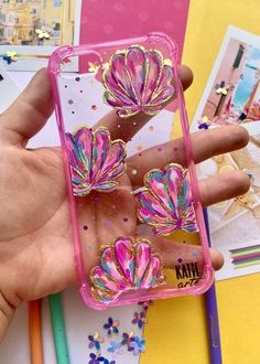 a hand holding a pink phone case with colorful flowers on the front and back cover