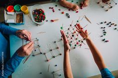 two adults and one child working on an art project with popssticks in front of them