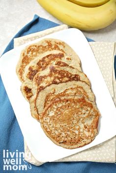 a white plate topped with pancakes next to bananas