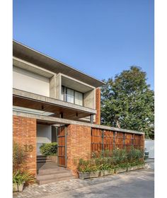 the entrance to an apartment building with brick walls and wooden doors, surrounded by greenery