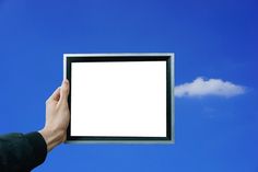 a person holding up an empty square in front of a blue sky with a white cloud