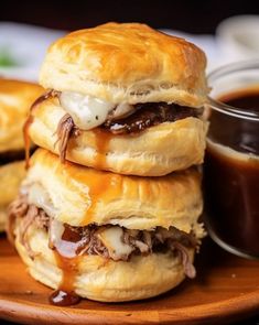 a stack of pastries sitting on top of a wooden plate next to a cup of sauce