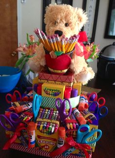 a teddy bear sitting on top of a pile of crayons and pencils