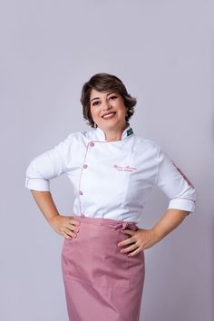 a woman standing with her hands on her hips wearing a chef's coat and pink skirt