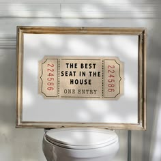 a toilet in a bathroom with a framed sign above it that says the best seat in the house