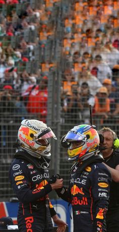 two men standing next to each other in front of a crowd on a race track