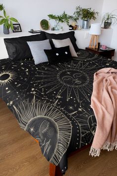 a black and white bedspread with an intricate design on it, surrounded by potted plants