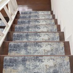 an old carpeted stair case with blue and white rugs on the bottom floor