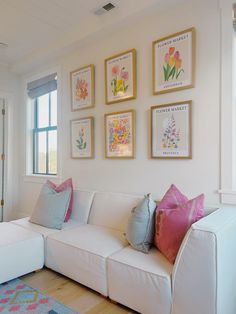 a white couch sitting in front of a window next to a wall with pictures on it