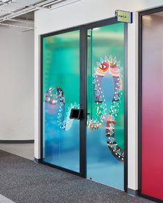 two colorful glass doors with designs on them in an office building or conference room area