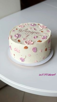 a white cake sitting on top of a table covered in pink and gold confetti