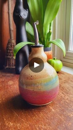 a vase sitting on top of a wooden table next to a cat figurine