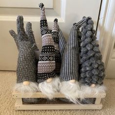 four knitted hand puppets sitting on top of a wooden sled in front of a door