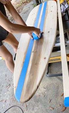 a person sanding down a surfboard with blue tape on it's sides