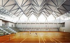 an indoor tennis court with people playing on the court and empty seats in the background