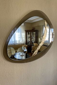 a mirror hanging on the wall reflecting a living room with couches and tables in it