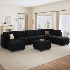 a living room with a black sectional couch and ottoman in front of two large windows