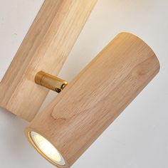 a wooden light fixture mounted on the wall next to a white wall with a yellow light