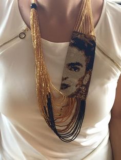 a woman wearing a white shirt and gold chain necklace with a face on the front