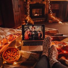 a laptop computer sitting on top of a bed next to a person's feet