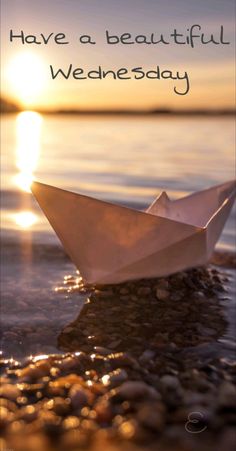 a white paper boat floating on top of a lake next to the ocean with text that reads, i have a beautiful wednesday