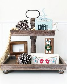 three tiered trays with decorative items on them, including pine cones and coffee cups