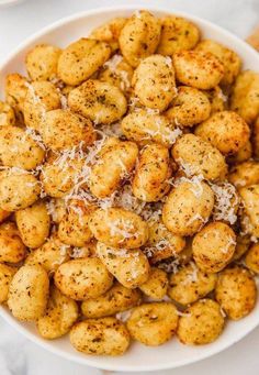 a white bowl filled with cheesy tater tots covered in parmesan cheese