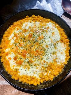 a skillet filled with macaroni and cheese on top of a wooden table