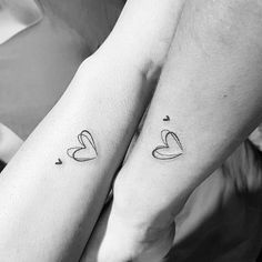 two people holding hands with tattoos on their arms and one has a heart in the middle