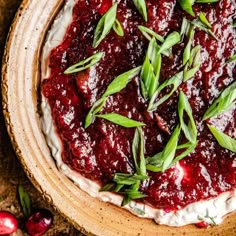 a wooden bowl filled with whipped cream and cranberry sauce on top of a table