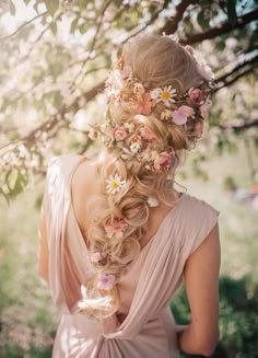 a woman with long hair and flowers in her hair is standing under a tree branch