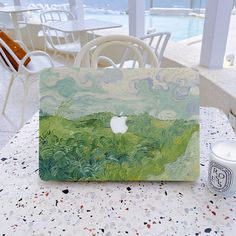 an apple painting sitting on top of a table next to a cup and candle holder