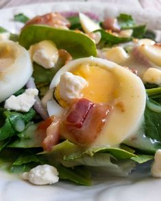 a salad with hard boiled eggs and spinach leaves is shown on a white plate