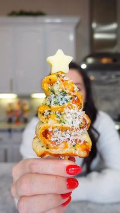 a woman holding up a christmas tree shaped pastry with cheese and spinach on it