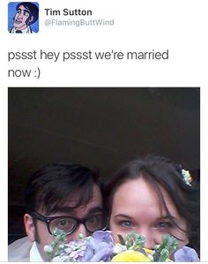 a man and woman are posing for a photo with flowers in front of their faces