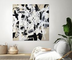 an abstract painting hangs on the wall next to a chair and potted plant in a white room