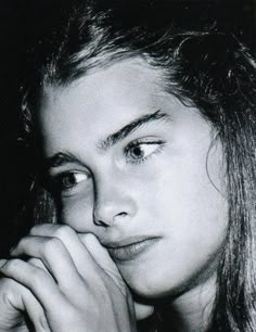 a black and white photo of a woman with her hand on her chin looking at the camera