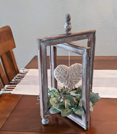 a wooden table topped with a vase filled with flowers and two hearts hanging from it