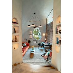 a living room filled with lots of furniture and bookshelves next to a window