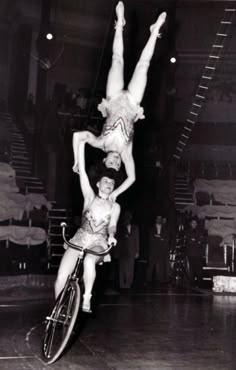 two women are doing tricks on bicycles in an old black and white photo